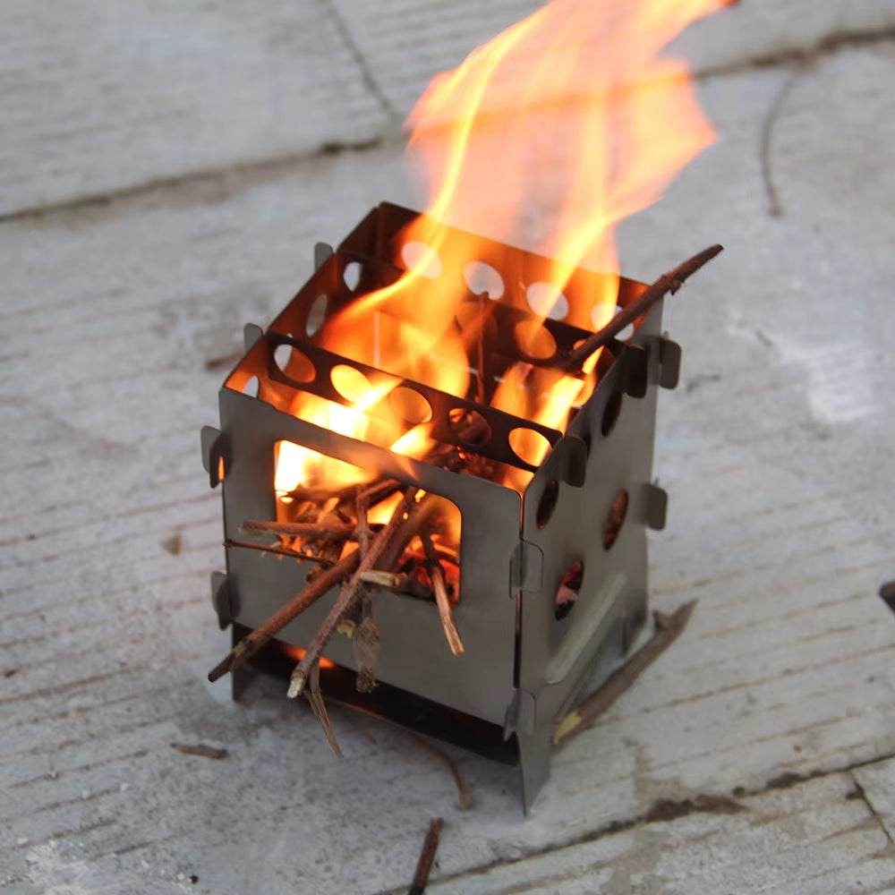Lightweight titanium stainless steel folding camping stove with open flame.